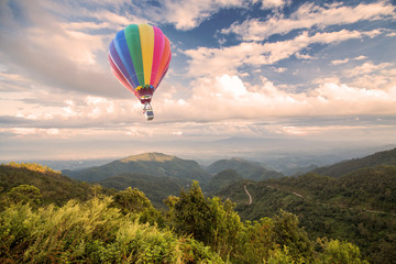 Naklejka premium Hot air balloon over forest mountain and blue sky
