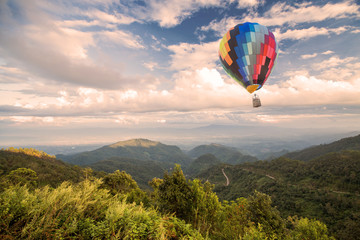 Hot air balloon over forest mountain and blue sky