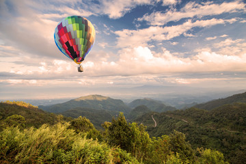 Naklejka premium Hot air balloon over forest mountain and blue sky