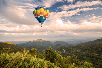 Hot air balloon over forest mountain and blue sky