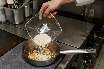 Chef is pouring rice to stewpan