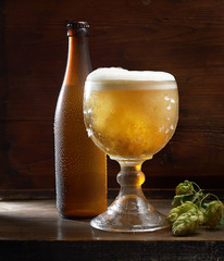 Bottle and glass of beer on the wooden table over black background