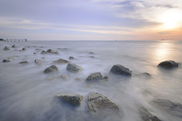 Fototapeta premium Motion waves on stones at the beach. Motion Blur due to Slow Shutter Speed.