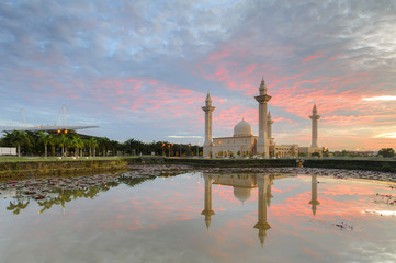 Fototapeta premium View and reflection of Bukit Jelutong Mosque with stunning blue and red clouds and ray of lights during sunrise.