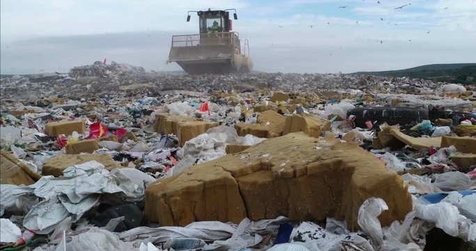 Bulldozer flattening garbage in landfill waste site