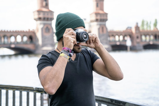 Germany, Berlin, man taking pictures with camera in front of Oberbaum Bridge