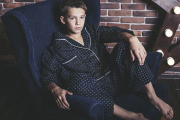 Beautiful trendy teen boy sitting on a chair at home © kuzmichstudio