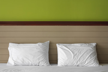 dual white pillow on bed at headboard and green wall