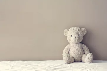 Fotobehang vintage teddy bear sit on the right side white bed at headboard © kornnphoto