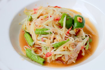 Green Papaya Salad (Som tum Thai) in white dish on wood table, Thai cuisine spicy delicious