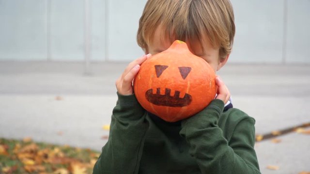 junger bub spielt mit k&uuml;rbis zu halloween