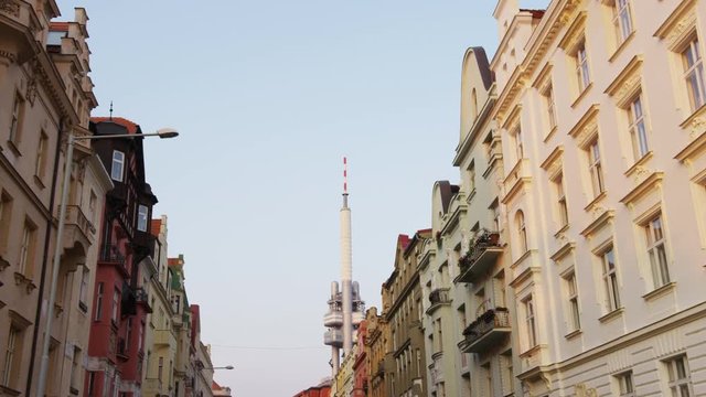 A left moving shot looking up at the street building facades with the Zizkov tower in the distance. 4k.