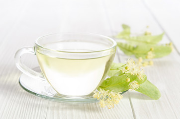 Glass cup of tea with linden on white wooden table