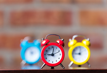 Three little red alarm clocks on table
