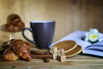 cup with tea croissant book