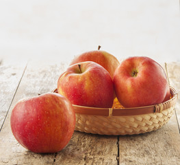 Fresh harvest of apples. Nature theme with red grapes and basket on wooden background. Nature fruit concept.