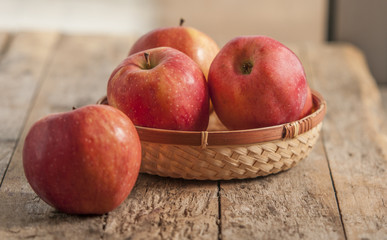Fresh harvest of apples. Nature theme with red grapes and basket on wooden background. Nature fruit concept.