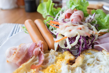 Breakfast closeup Fried egg, ham, bacon, sausage, salad and vegetables