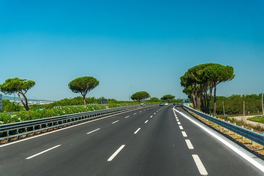 View of the highway with trees and blue sky in Italy