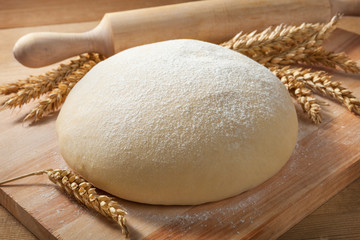 Fresh dough on a board with ears of wheat and rolling pin. - 124706519