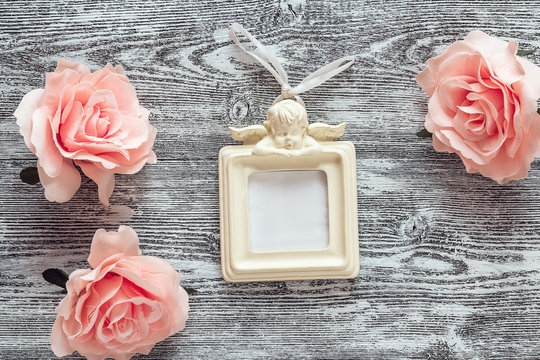 Background with pink roses and frame with an angel on the grey b