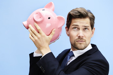 Businessman listening for cash in piggy bank