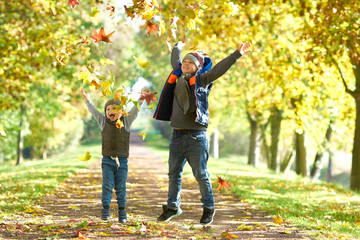 springende Kinder im Park, Laub werfen im Herbst