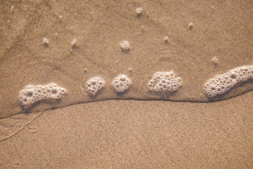 Wave bubble on golden sand