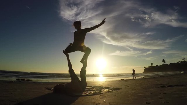 Beach sunset acroyoga routine 60fps, silhouette beauty shot.