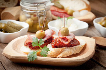 Tapas with sliced sausage, salami, olives and parsley.