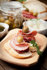 Tapas with sliced sausage, salami, olives and parsley.