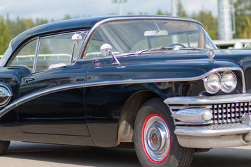 Close-up of an old car. Part of the exterior. An American classic. Chrome lining. Glass with reflection.