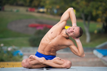 Athletic man doing yoga asanas in the park