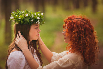 Naklejka premium incredibly beautiful woman and daughter standing in the wood