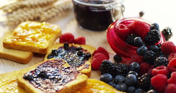 the hand of a young man in the morning for breakfast spreads of jam organic red fruits on a rusk . concept of organic jams and genuine and natural breakfast . Breakfast in the happy family