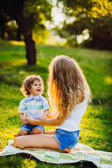 beautiful young mother with her son sitting in a park