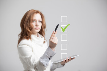 Young business woman checking on checklist box. Gray background.