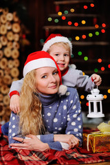 Mother and son in red caps of Santa Claus on a background  Christmas lights