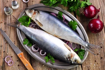 Fotobehang salted herring with red onion and parsley on the old wooden background. © chudo2307