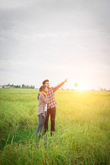 Fototapeta na wymiar Young hipster couple standing on field pointing look away to the