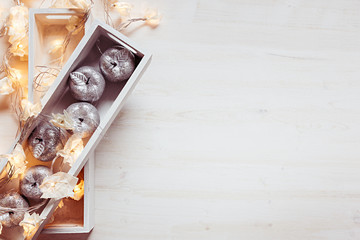 Christmas silver apples and lights burning in boxes  on a wooden white  background. Top view. Xmas background.