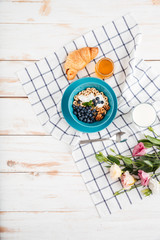 Oat cereals with berries and cream, cup of milk, flowers