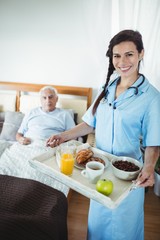 Obraz na płótnie Canvas Nurse serving breakfast to senior man