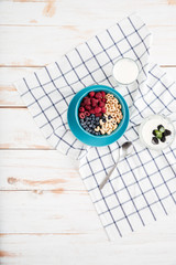 Top view of granola, berries, walnuts and milk