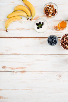 Bananas, berries, walnuts and honey on wooden background