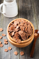 Chocolate cornflakes for breakfast in a bamboo plate on old wooden background. Selective focus.