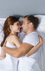 Young couple hugging on the bed in bedroom