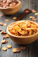 Cornflakes for breakfast in a bamboo plate on old wooden background. Selective focus.