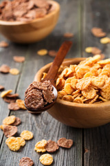 Cornflakes for breakfast in a bamboo plate on old wooden background. Selective focus.
