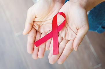 Close up woman showing red ribbon HIV, AIDS awareness ribbon, healthcare and medicine concept.